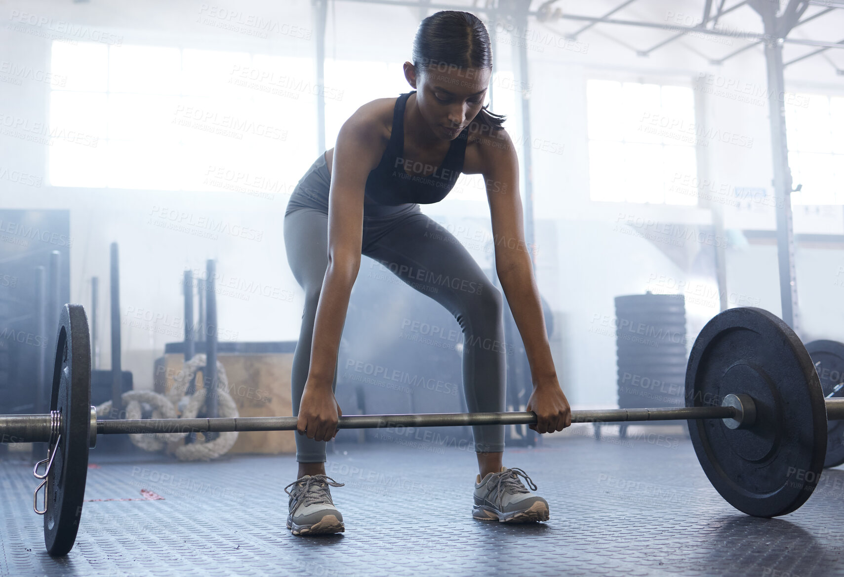 Buy stock photo Shot of a sporty young woman exercising with a barbell in a gym