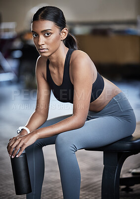 Buy stock photo Portrait of a sporty young woman taking a break while exercising in a gym