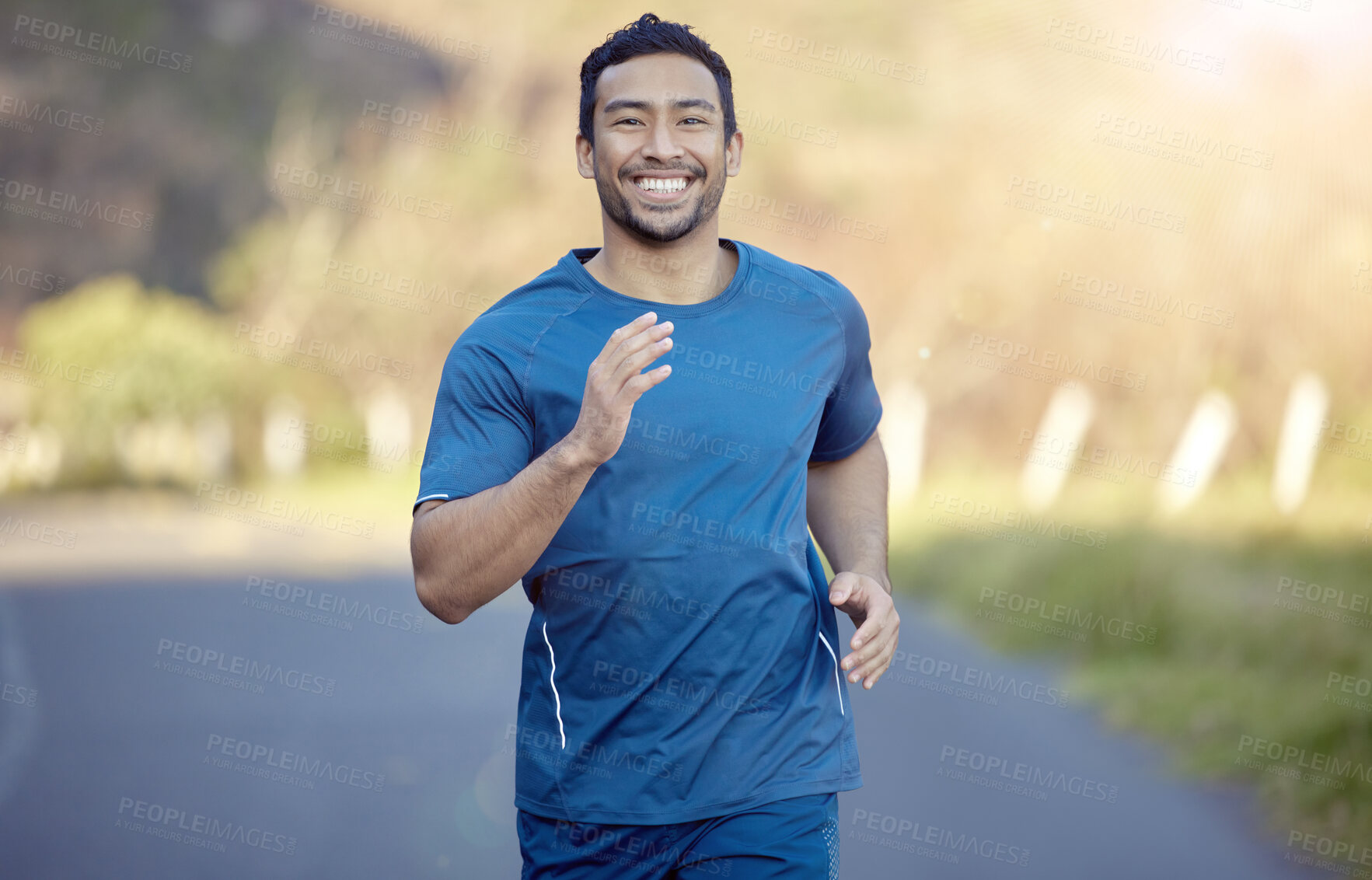 Buy stock photo Shot of a handsome young man running alone outside during the day