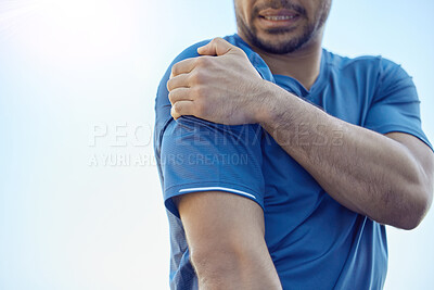 Buy stock photo Cropped shot of an unrecognisable man standing alone and suffering from shoulder pain during his outdoor workout