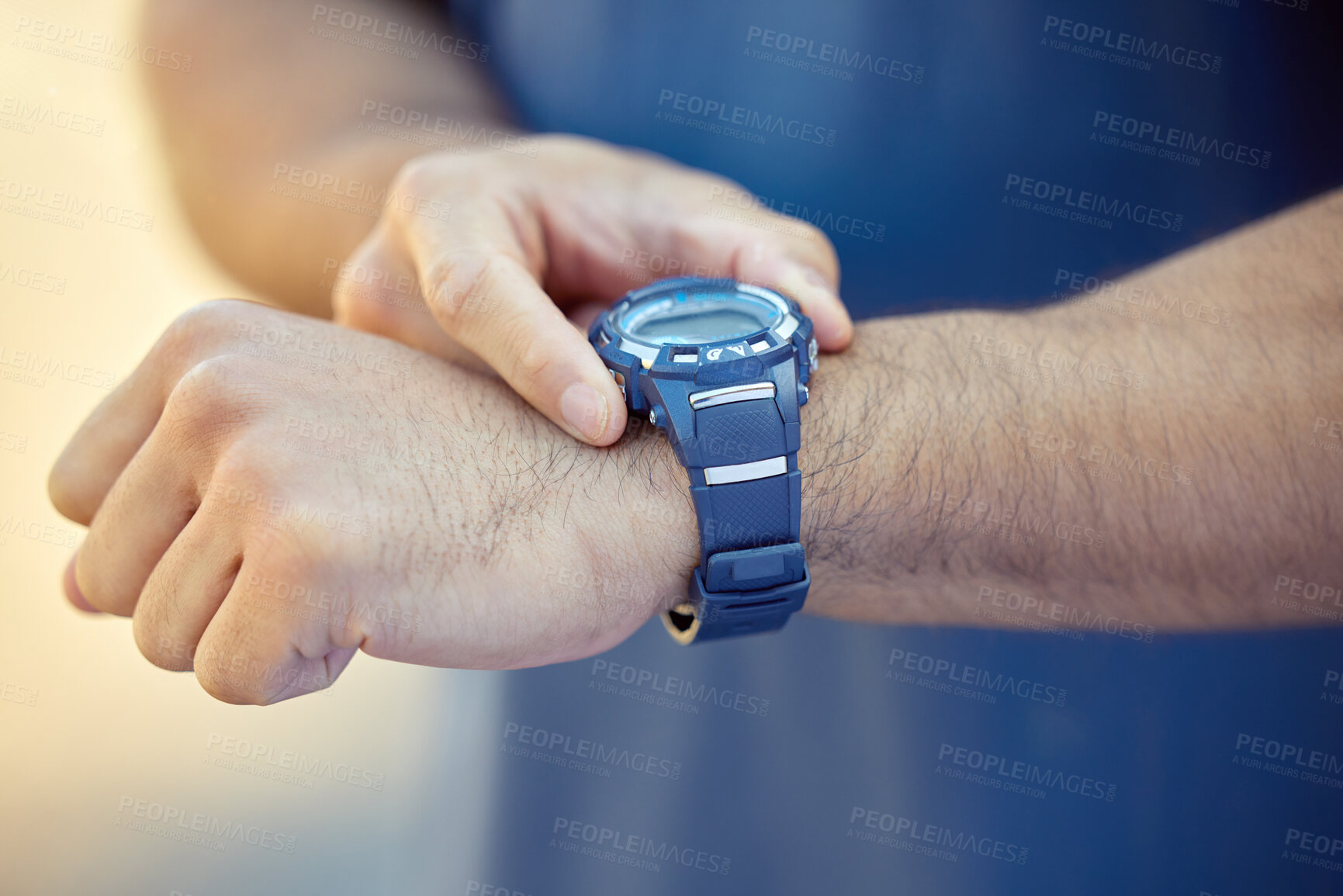 Buy stock photo Cropped shot of an unrecognisable man standing alone and setting a timer on his watch during his outdoor workout