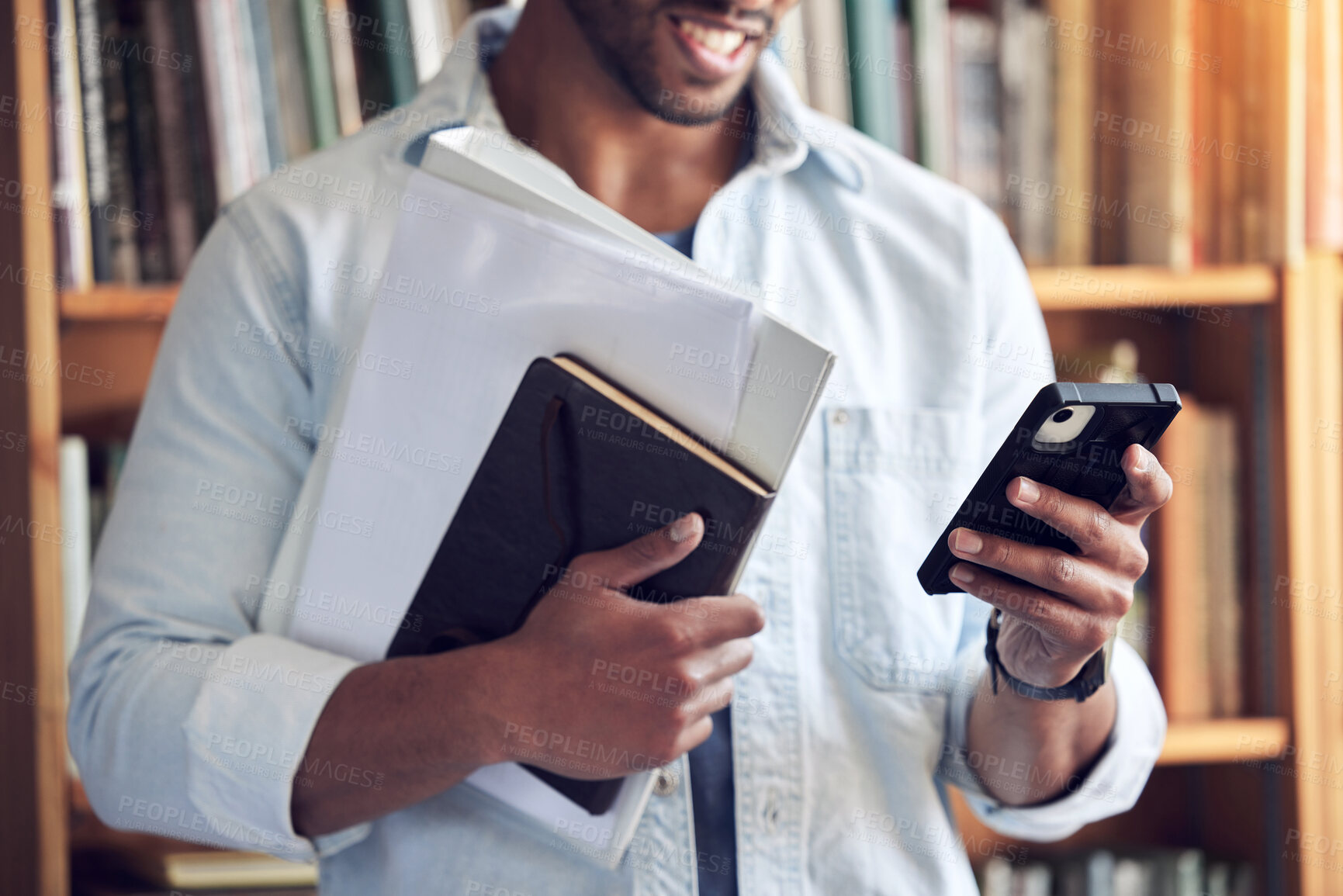 Buy stock photo Shot of a man using a smartphone in a library at university