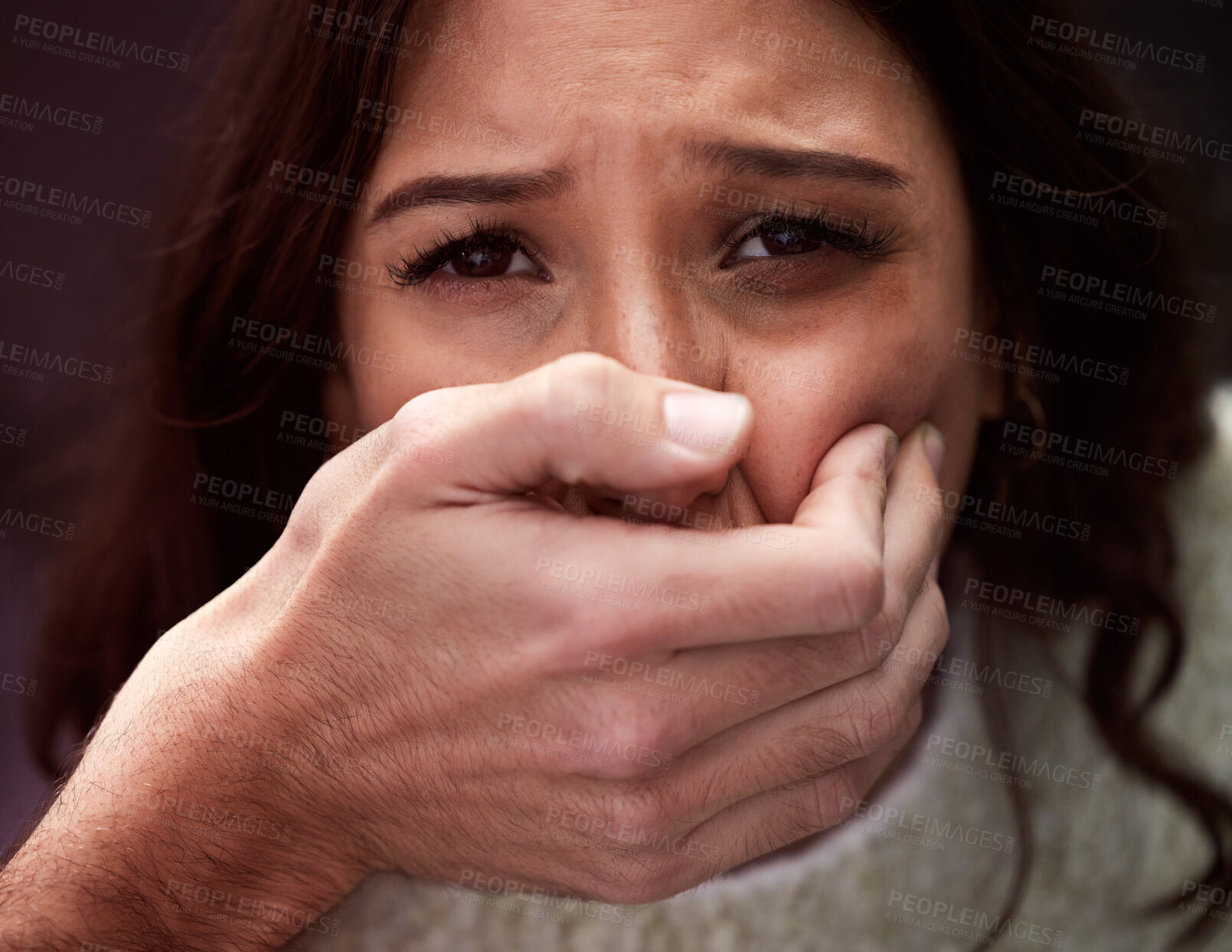 Buy stock photo Shot of a scared young woman’s mouth being covered by an unrecognisable man’s hand