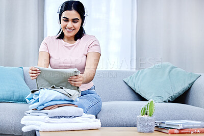 Buy stock photo Shot of a young woman folding clothes at home