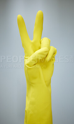 Buy stock photo Shot of a hand showing the peace sign while wearing yellow rubber gloves