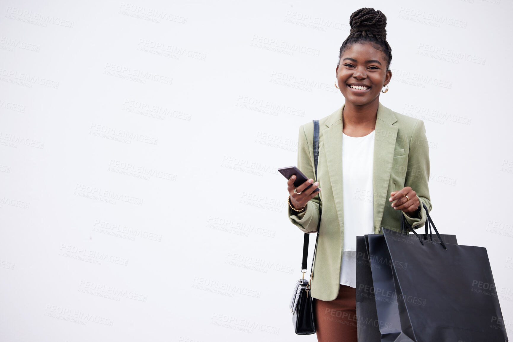 Buy stock photo Shot of a woman holding shopping bags while using her smartphone against a studio background