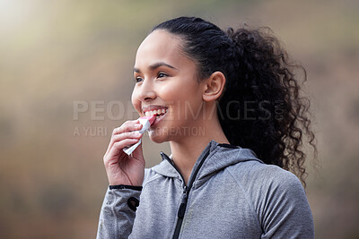 Buy stock photo Shot of a fit young woman eating a pink bar while out for a workout