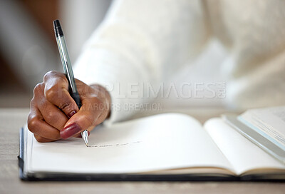 Buy stock photo Shot of an unrecognisable woman making notes in a book while studying at home