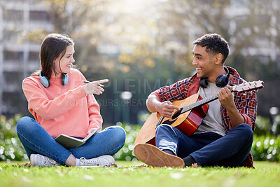 Buy stock photo Shot of a young man and woman playing the guitar on a study break at college
