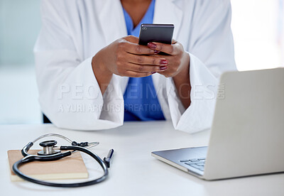 Buy stock photo Shot of an unrecognizable doctor using a phone and laptop at work
