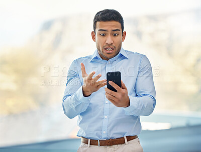 Buy stock photo Shot of a young handsome businessman looking shocked while reading a text on his smartphone