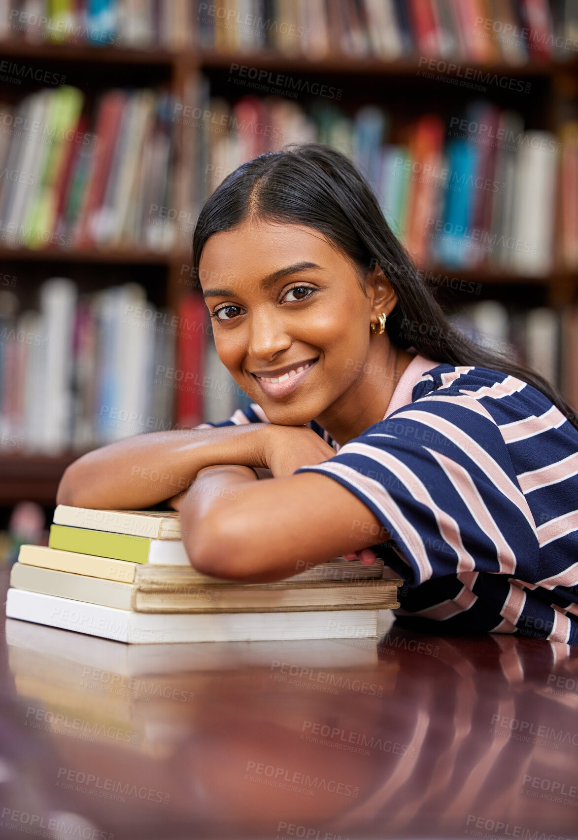 Buy stock photo Shot of a young woman resting on a pile of books in a college library