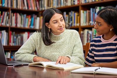 Buy stock photo Shot of two young women having a discussion in a college library