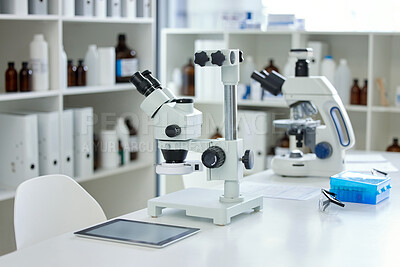 Buy stock photo Shot of a microscope and digital tablet on a table in an empty lab