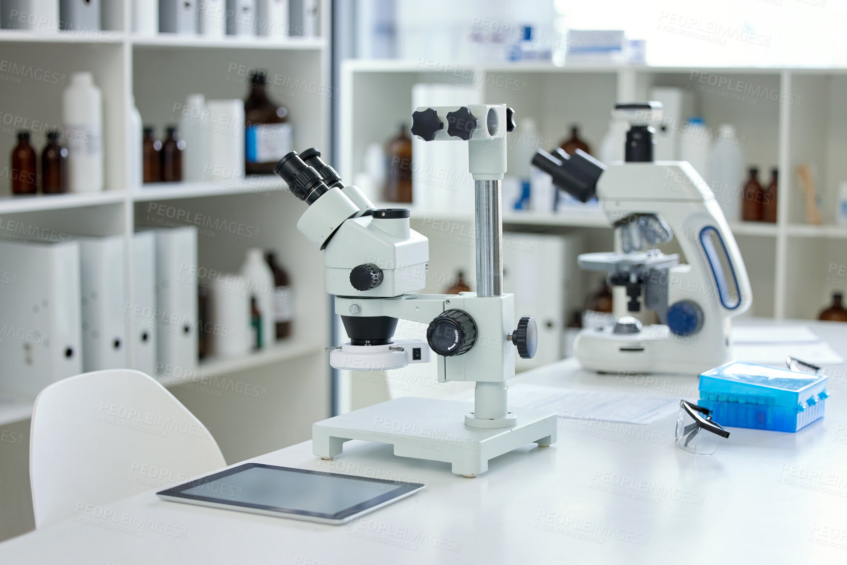 Buy stock photo Shot of a microscope and digital tablet on a table in an empty lab