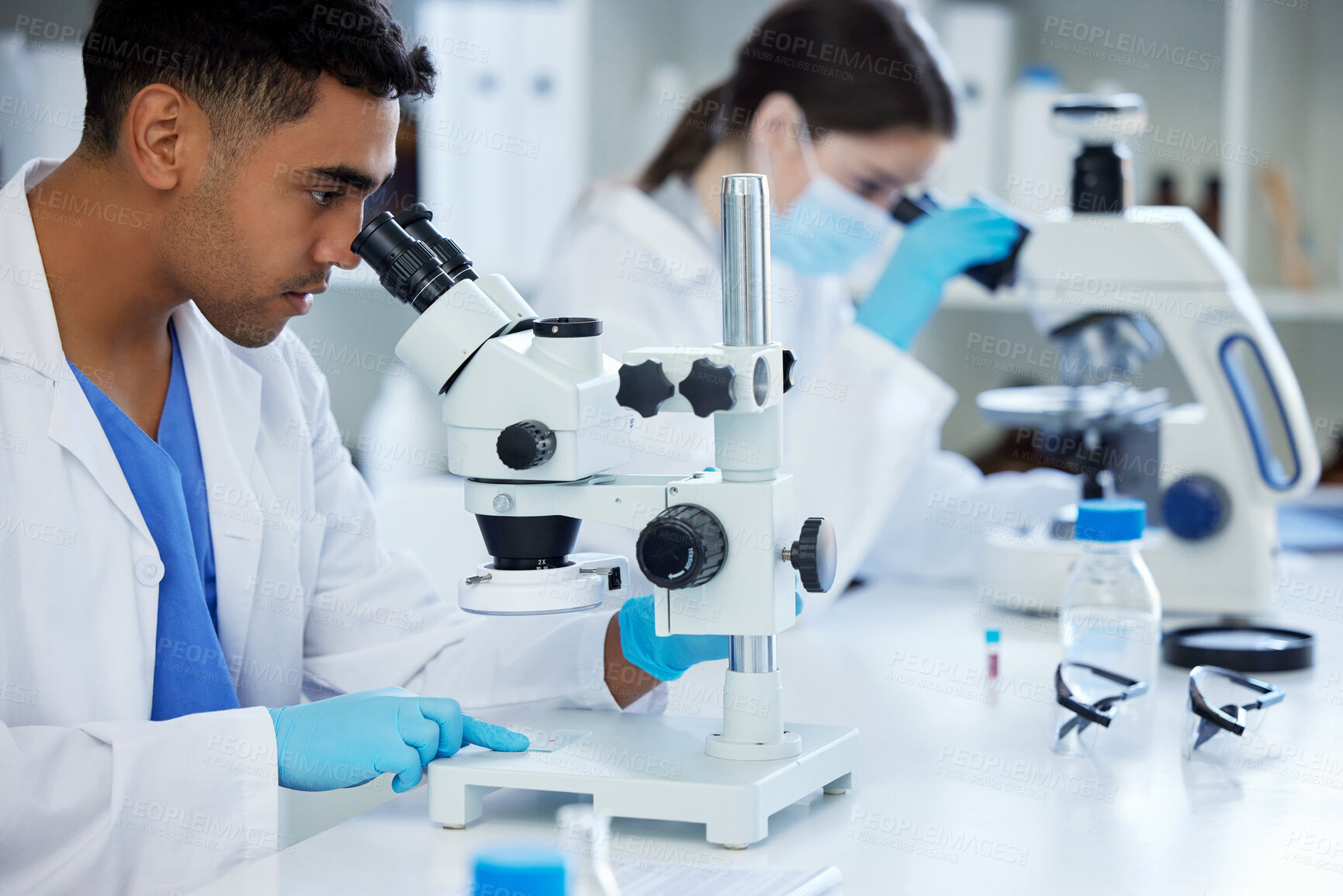 Buy stock photo Shot of two scientists using microscopes in a lab