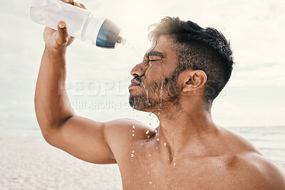 Buy stock photo Shot of a sporty young man pouring water over his face while out for a run