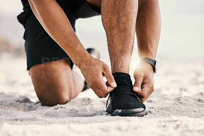 Buy stock photo Cropped shot of an unrecognizable man tying his shoelaces while out for a workout