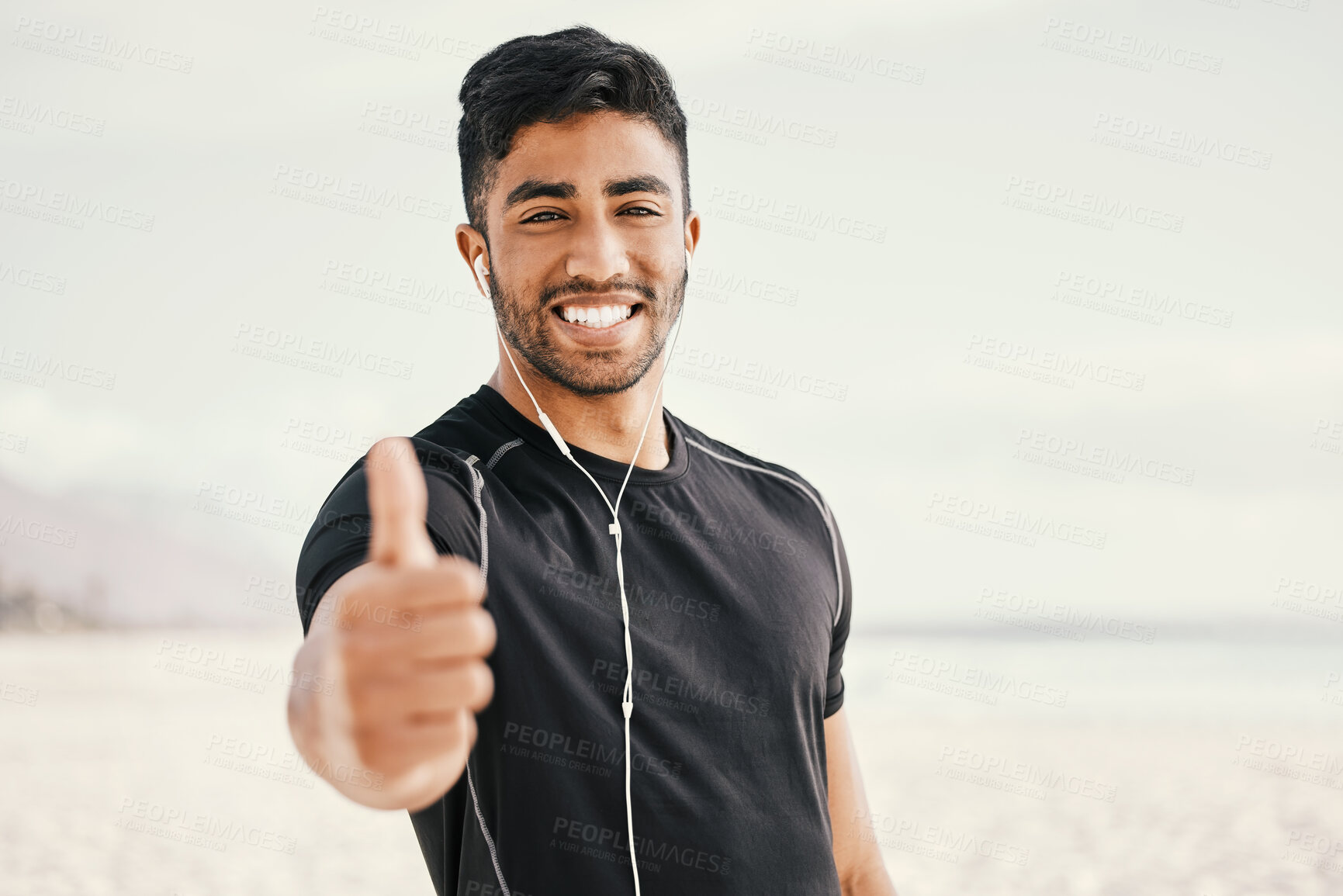 Buy stock photo Shot of a sporty young man wearing earphones and showing thumbs up while standing outside