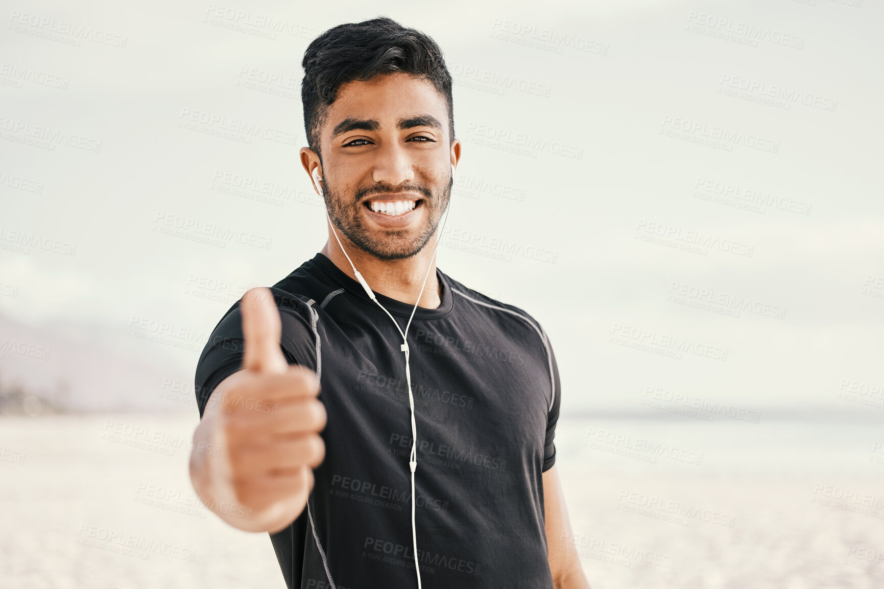 Buy stock photo Happy, man and fitness with thumbs up and earphones for listening to music on run or beach workout. Smile, male person and hand for success gesture with victory or achievement in exercise goals