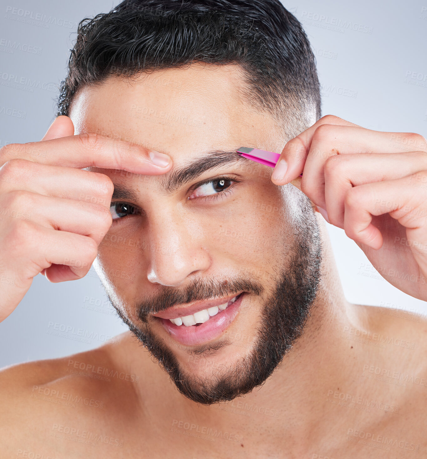 Buy stock photo Studio shot of a handsome young man plucking his eyebrows against a grey background