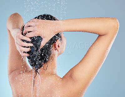 Buy stock photo Rearview studio shot of an attractive young woman washing her hair while taking a shower against a blue background