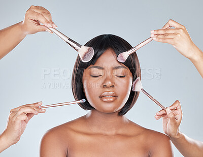 Buy stock photo Studio shot of an attractive young woman having makeup applied to her face and looking unhappy against a grey background