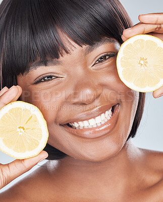 Buy stock photo Studio shot of an attractive young woman holding a lemon to her face against a grey background