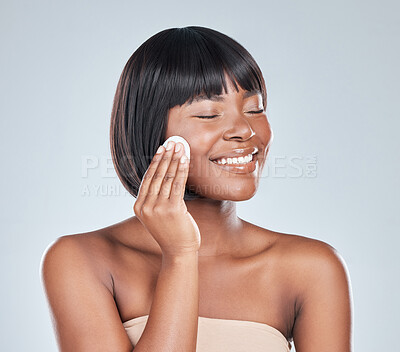 Buy stock photo Studio shot of an attractive young woman wiping her face with cotton against a grey background
