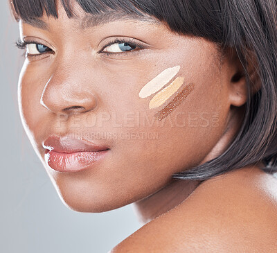 Buy stock photo Studio shot of an attractive young woman applying different shades of foundation to her face against a grey background