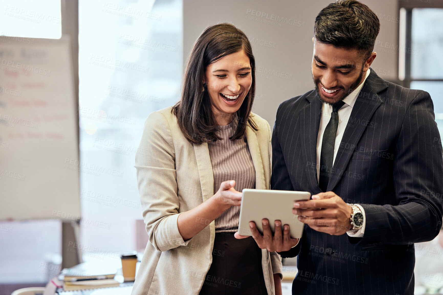 Buy stock photo Shot of two young businesspeople using a digital tablet at work