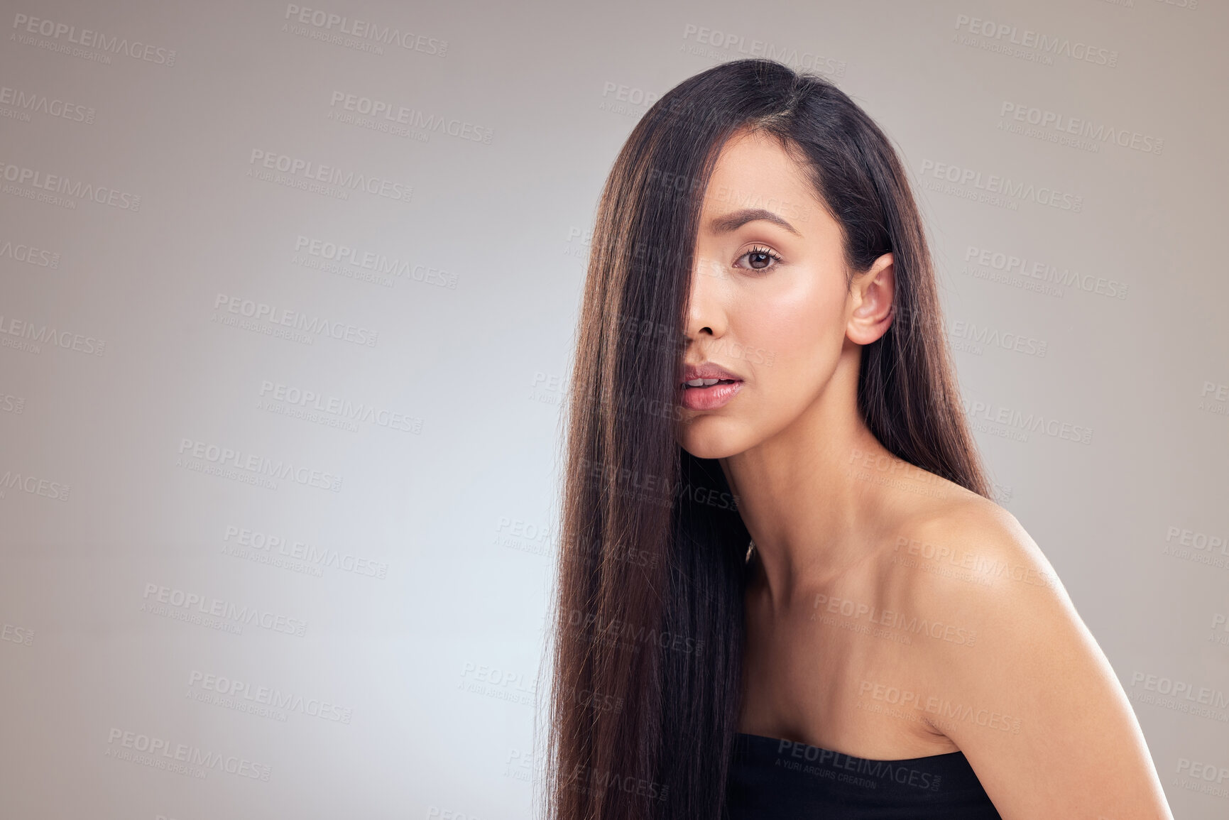 Buy stock photo Shot of an attractive young woman posing alone in the studio with her hair covering half of her face