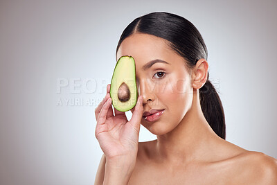Buy stock photo Studio portrait of a beautiful young woman posing with an avocado against a grey background