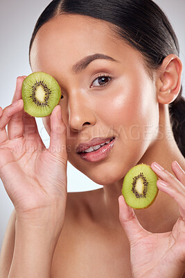Buy stock photo Studio portrait of a beautiful young woman posing with kiwi against a grey background