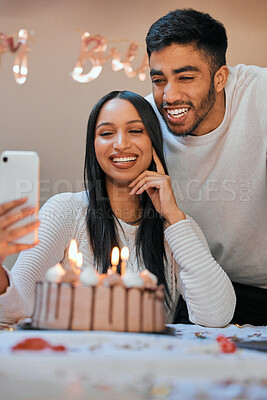 Buy stock photo Shot of a young couple using a cellphone while celebrating a birthday at home