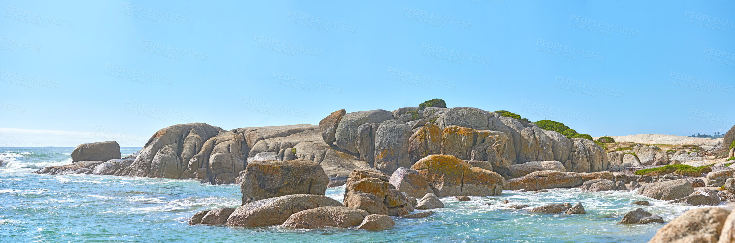 Buy stock photo Outdoor ocean landscape of calm water and big rocks in the sea. Peaceful nature view of the coast while outdoors. Beautiful relaxed beach day with clear blue sky and waves in the background outside.