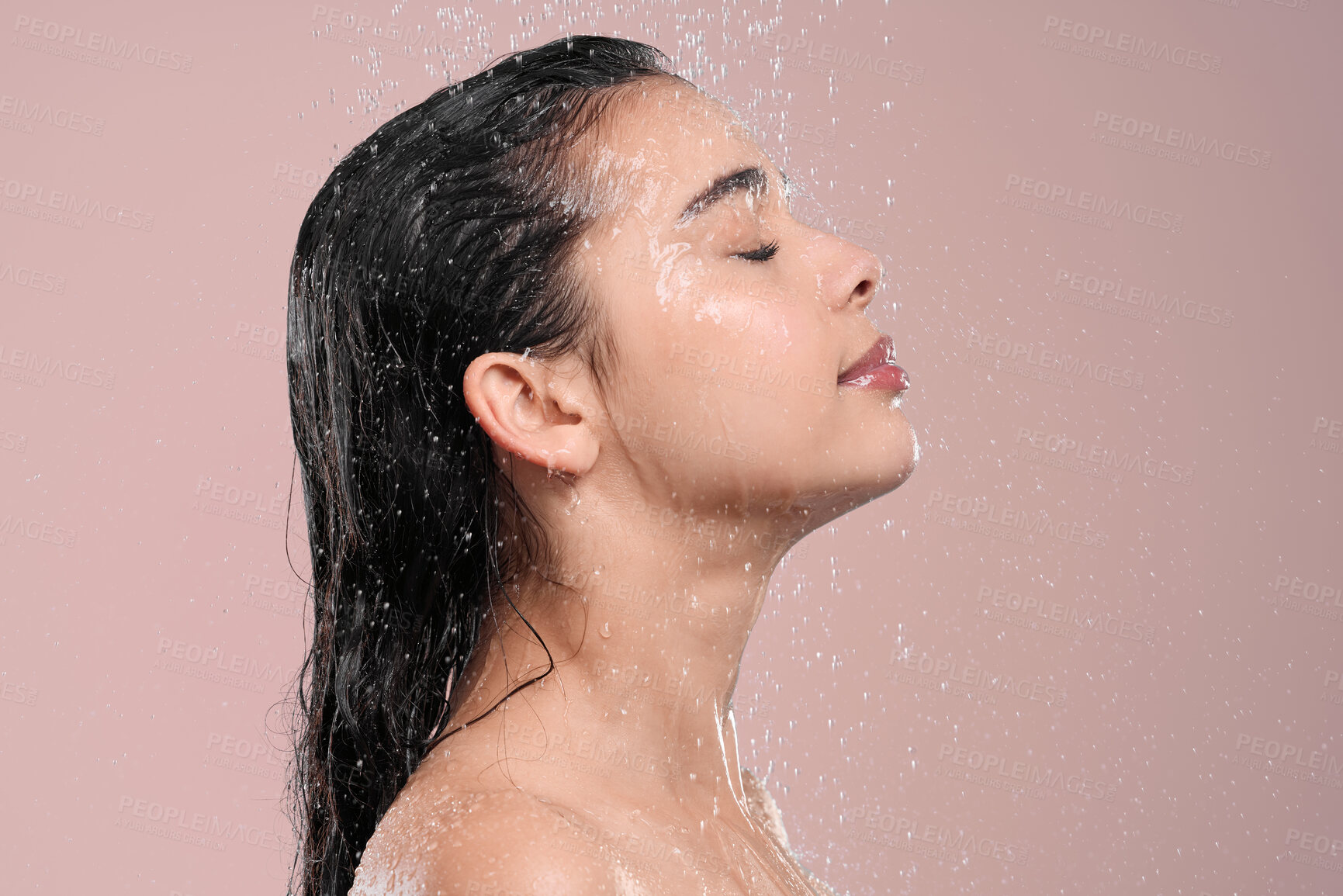 Buy stock photo Shot of a young woman washing her hair in a shower against a studio background