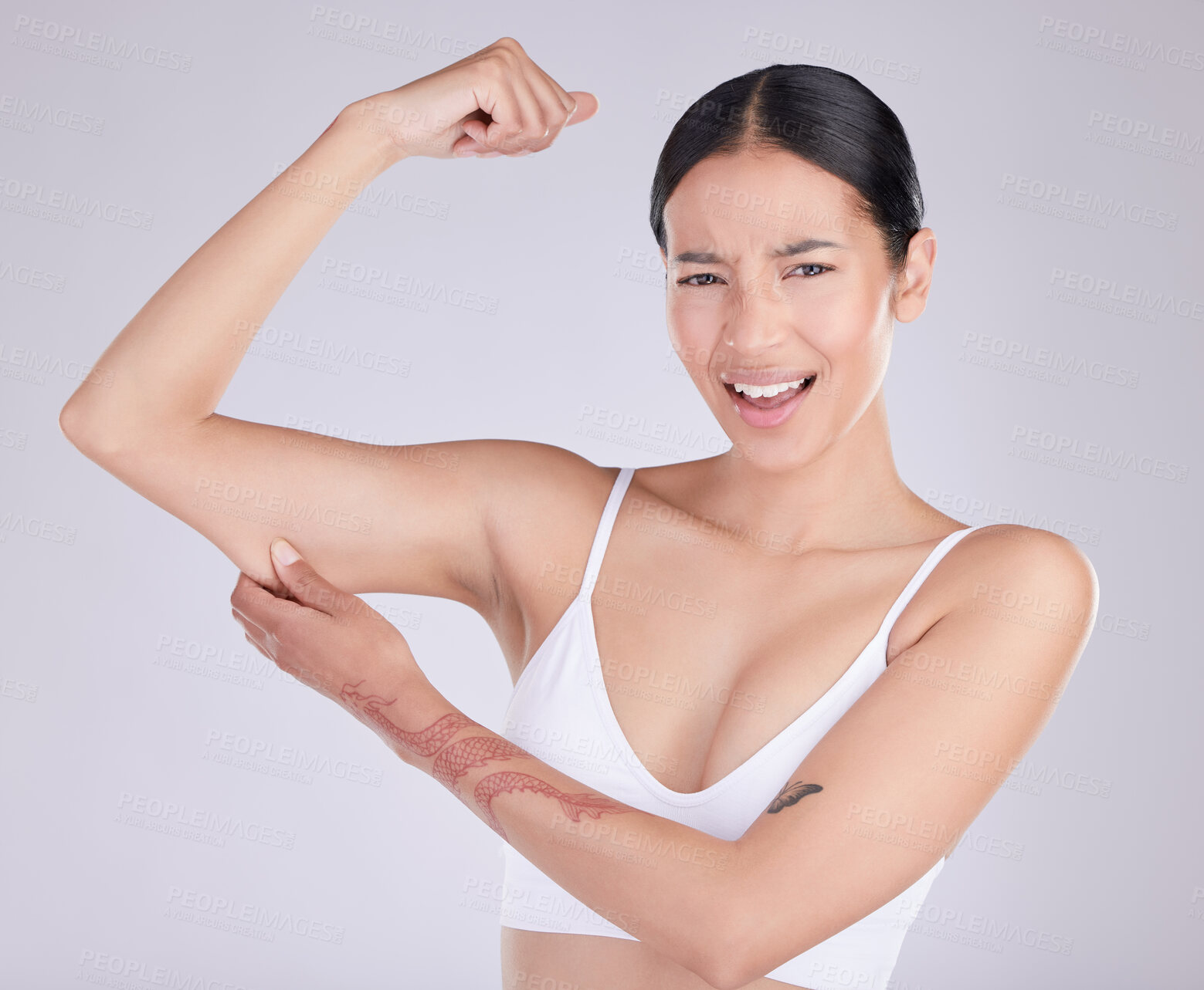 Buy stock photo Shot of an attractive young woman standing and tugging at excess skin on her arm