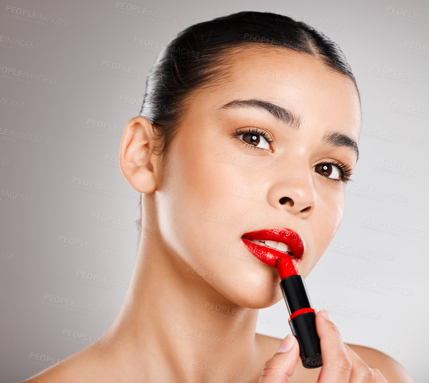 Buy stock photo Studio shot of an attractive young woman applying red lipstick against a grey background