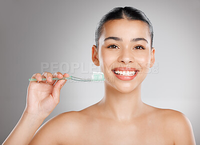 Buy stock photo Studio shot of an attractive young woman brushing her teeth against a grey background