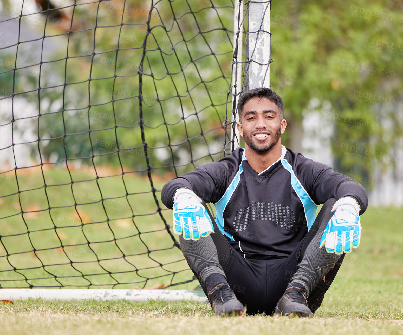 Buy stock photo Sports, soccer and portrait of a male goalkeeper sitting by the post on an outdoor field. Fitness, athlete and football player with a smile resting after a game, match or training on pitch in stadium
