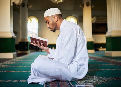 Buy stock photo Shot of a young muslim male reading scripture in a mosque