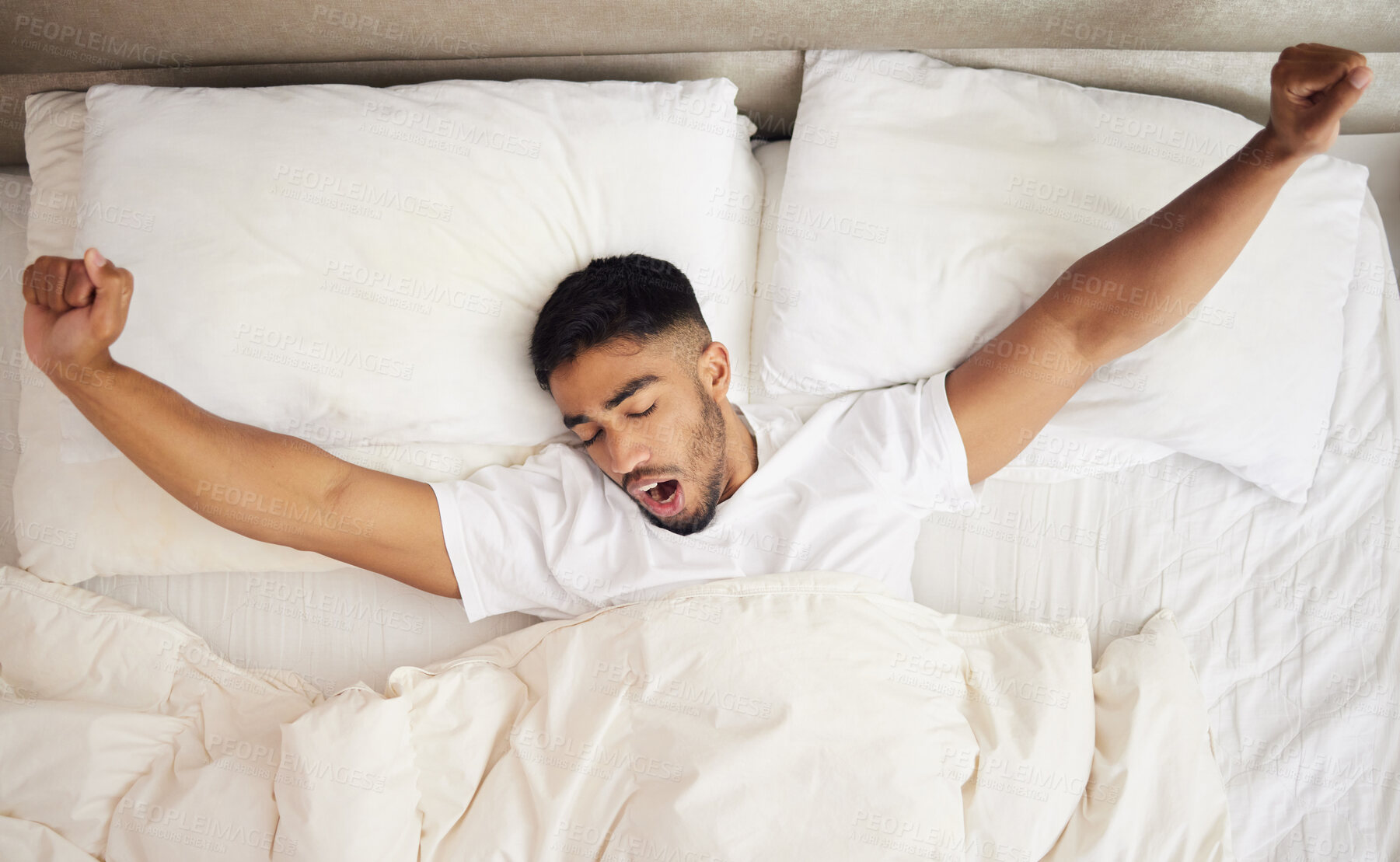 Buy stock photo Shot of a young man waking up in a bed at home