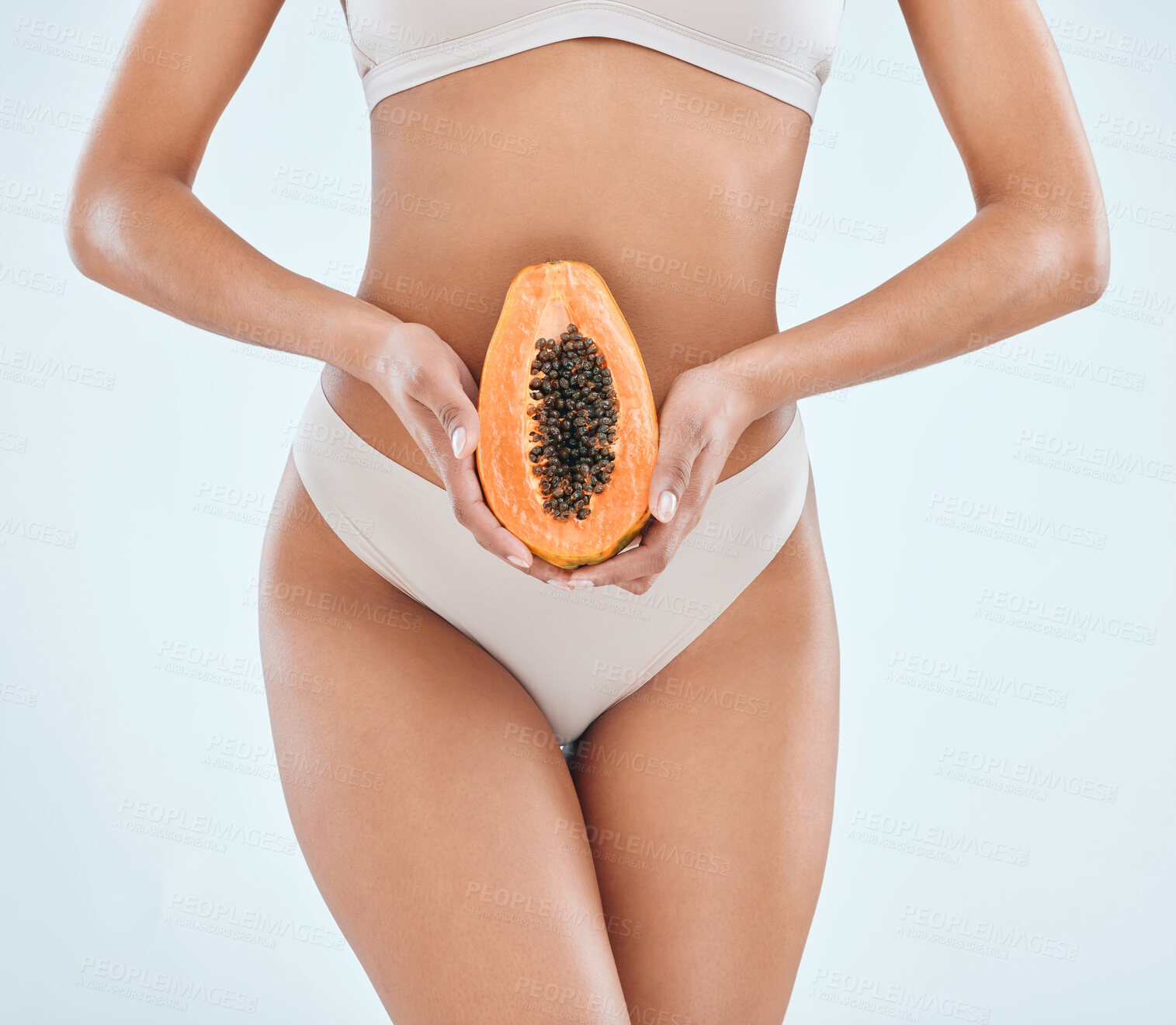 Buy stock photo Cropped shot of an unrecognisable woman standing alone in the studio and posing while holding a papaya