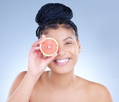 Buy stock photo Studio portrait of an attractive young woman holding a sliced grapefruit against a blue background
