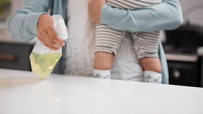 Buy stock photo Shot of a mother cleaning her kitchen counter while holding her baby