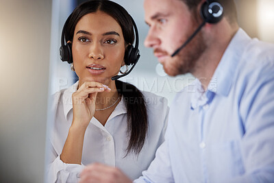 Buy stock photo Shot of two call centre agents working together on a computer in an office at night