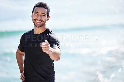 Buy stock photo Cropped portrait of a handsome young male athlete pointing towards the camera while working out on the beach