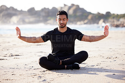 Buy stock photo Full length shot of a handsome young male athlete meditating on the beach