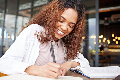 Buy stock photo Shot of a young businesswoman writing in a notebook while at a cafe